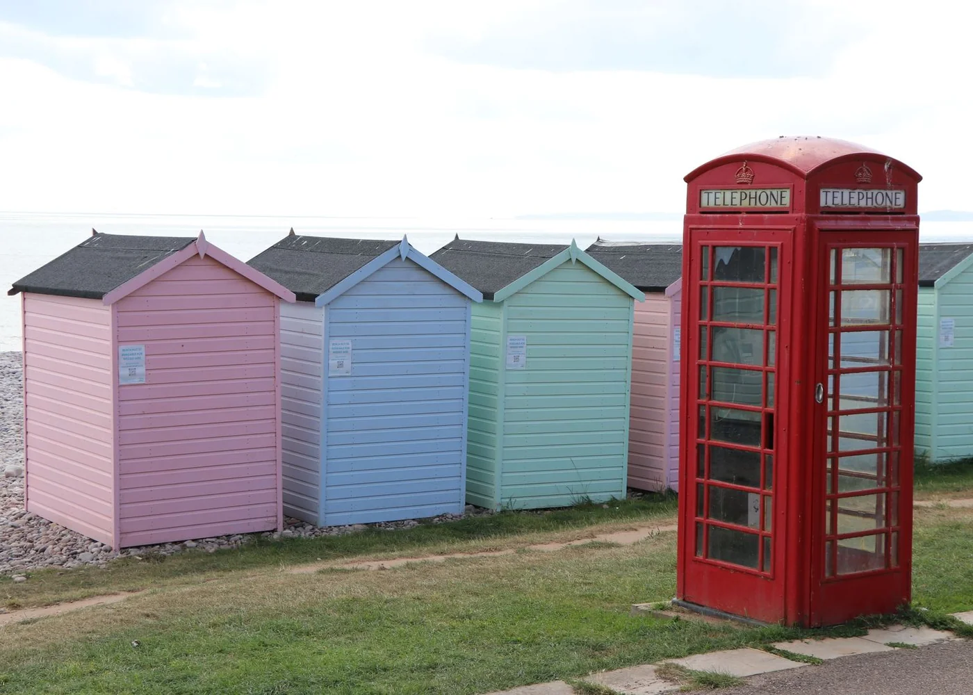 Pastel beach huts beside a red telephone box.