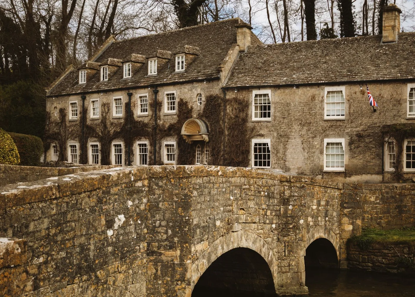 A stone bridge spanning a small river beside village houses.