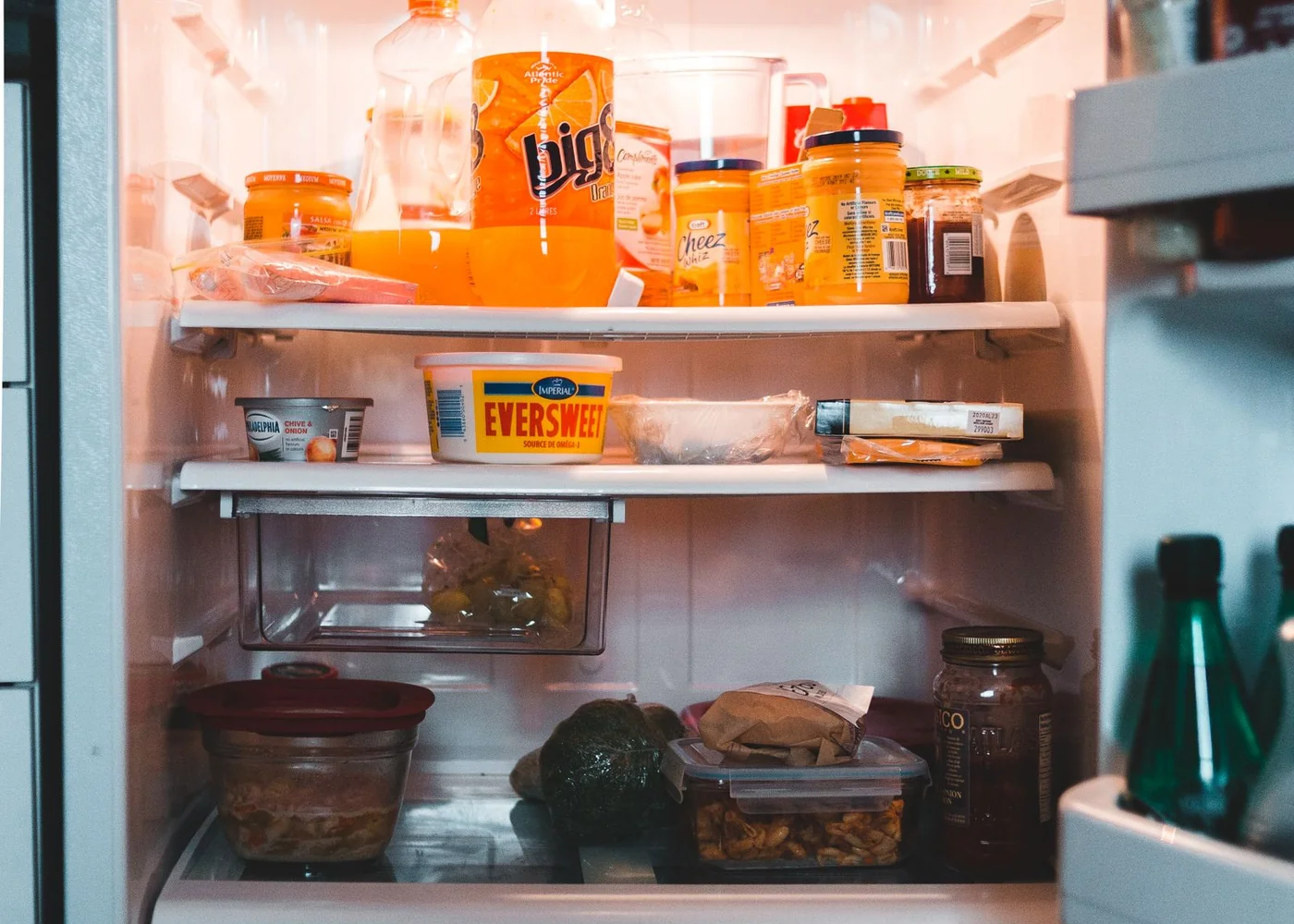 Food and drinks arranged on shelves inside an open fridge.