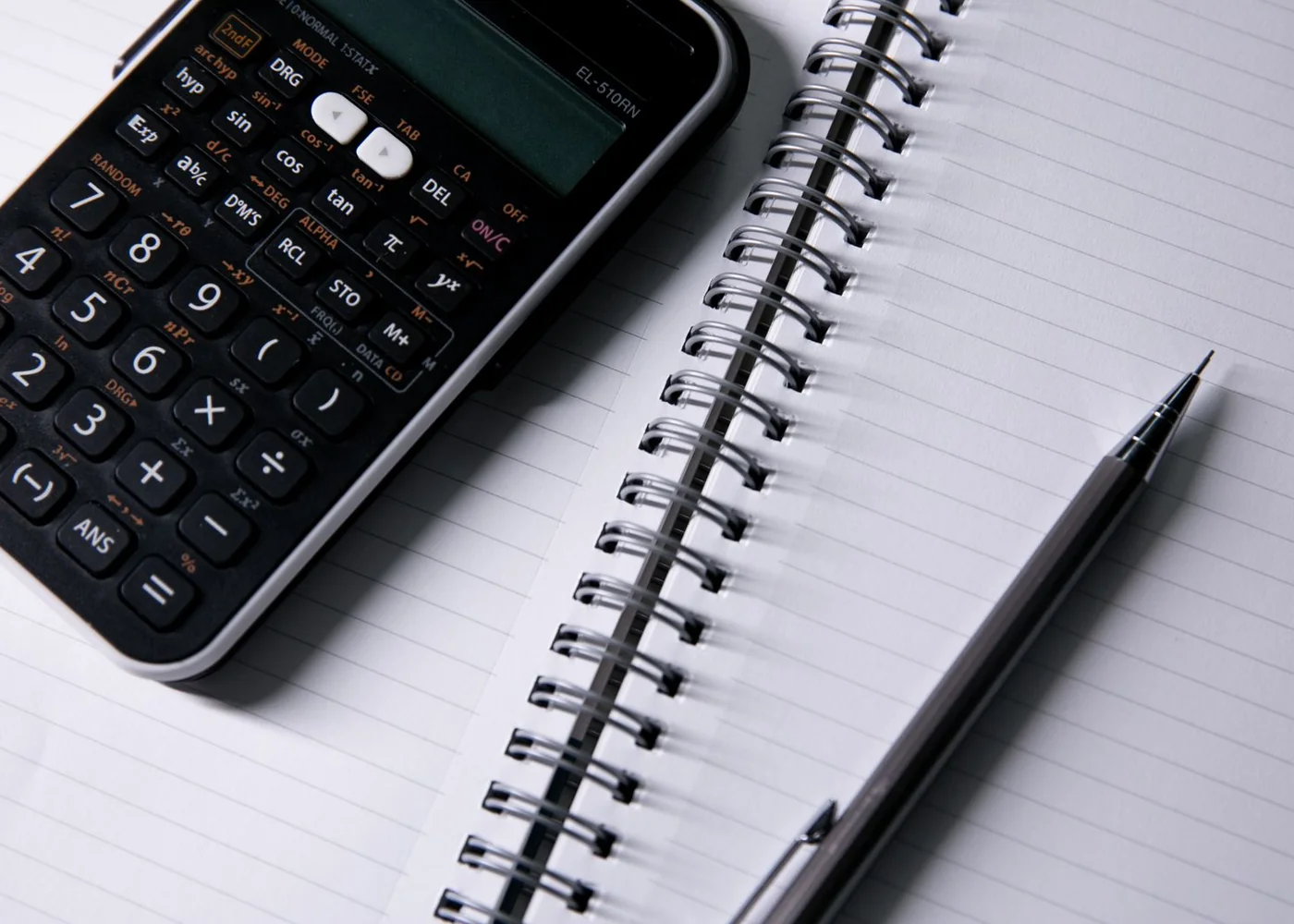 An open notebook with a calculator and pen.