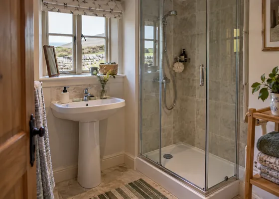 Compact bathroom with basin and shower cubicle.