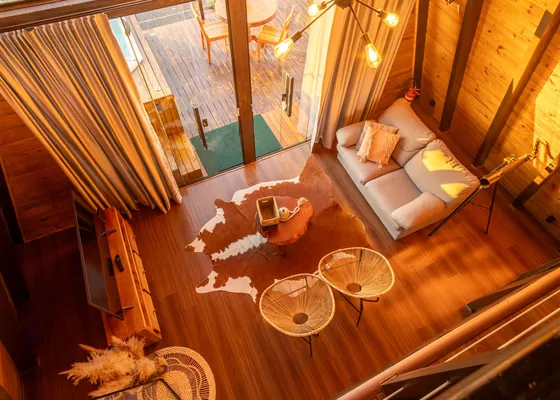 A compact timber sitting room with a sofa and small tables.