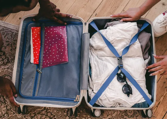 Clothes and travel items arranged in an open suitcase.