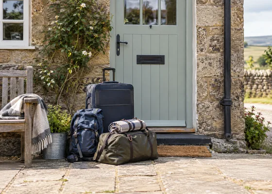 Travel bags beside a closed cottage entrance.