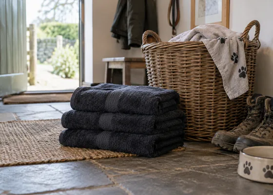 Folded dark towels beside a wicker laundry basket.